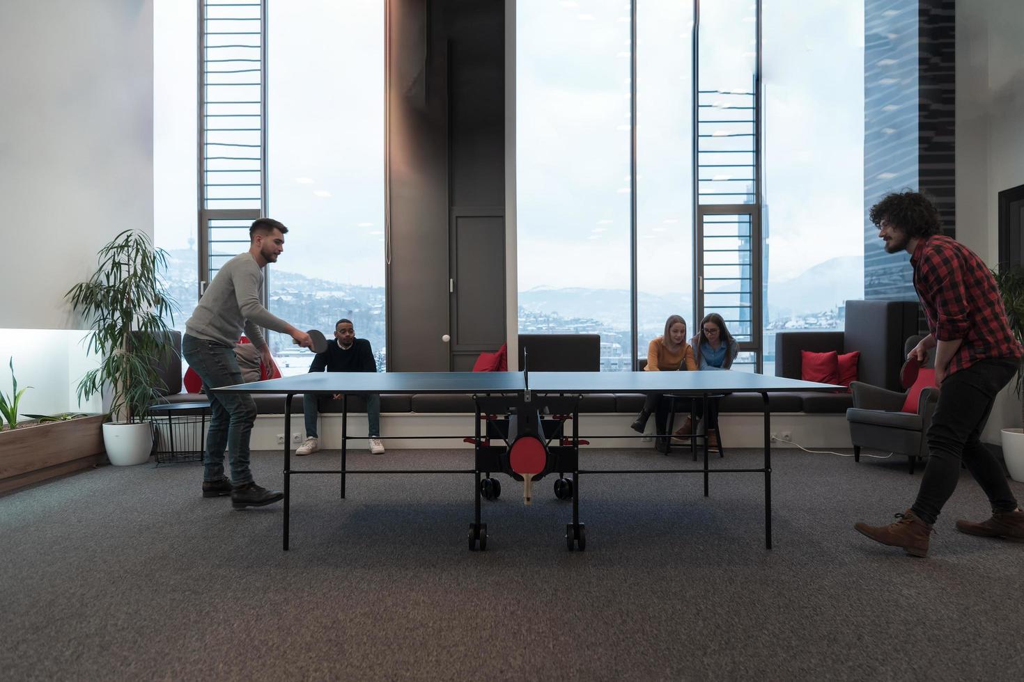 Two young start up business man playing table tennis at modern creative office space people group have meeting and brainstorming in background photo