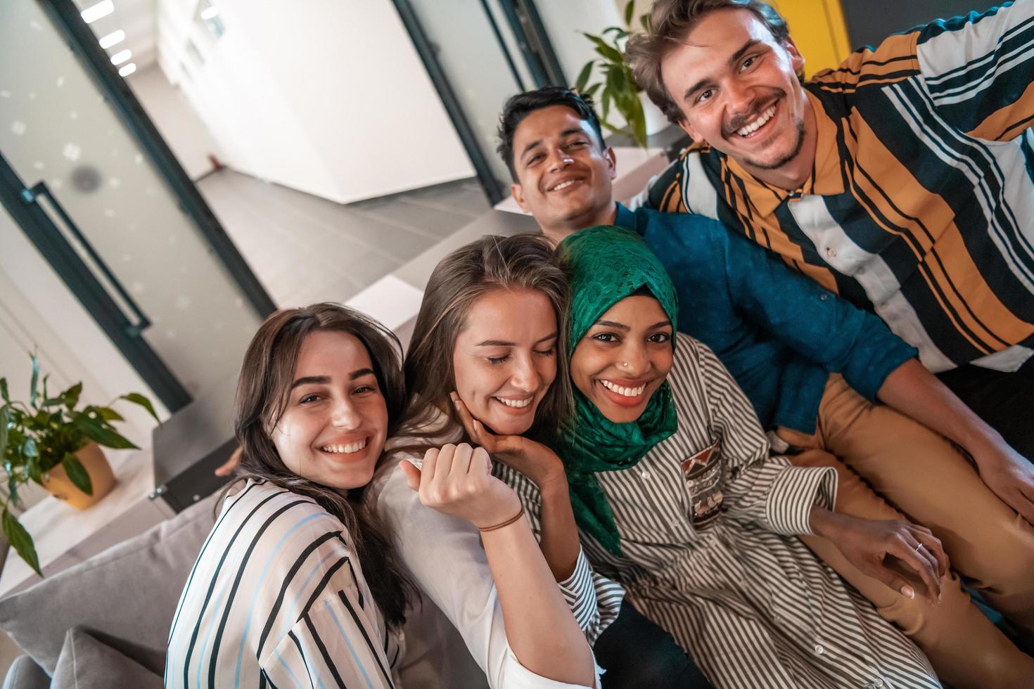 Group of business people during break from the work taking selfie picture while enjoying free time in relaxation area at modern open plan startup office. Selective focus photo