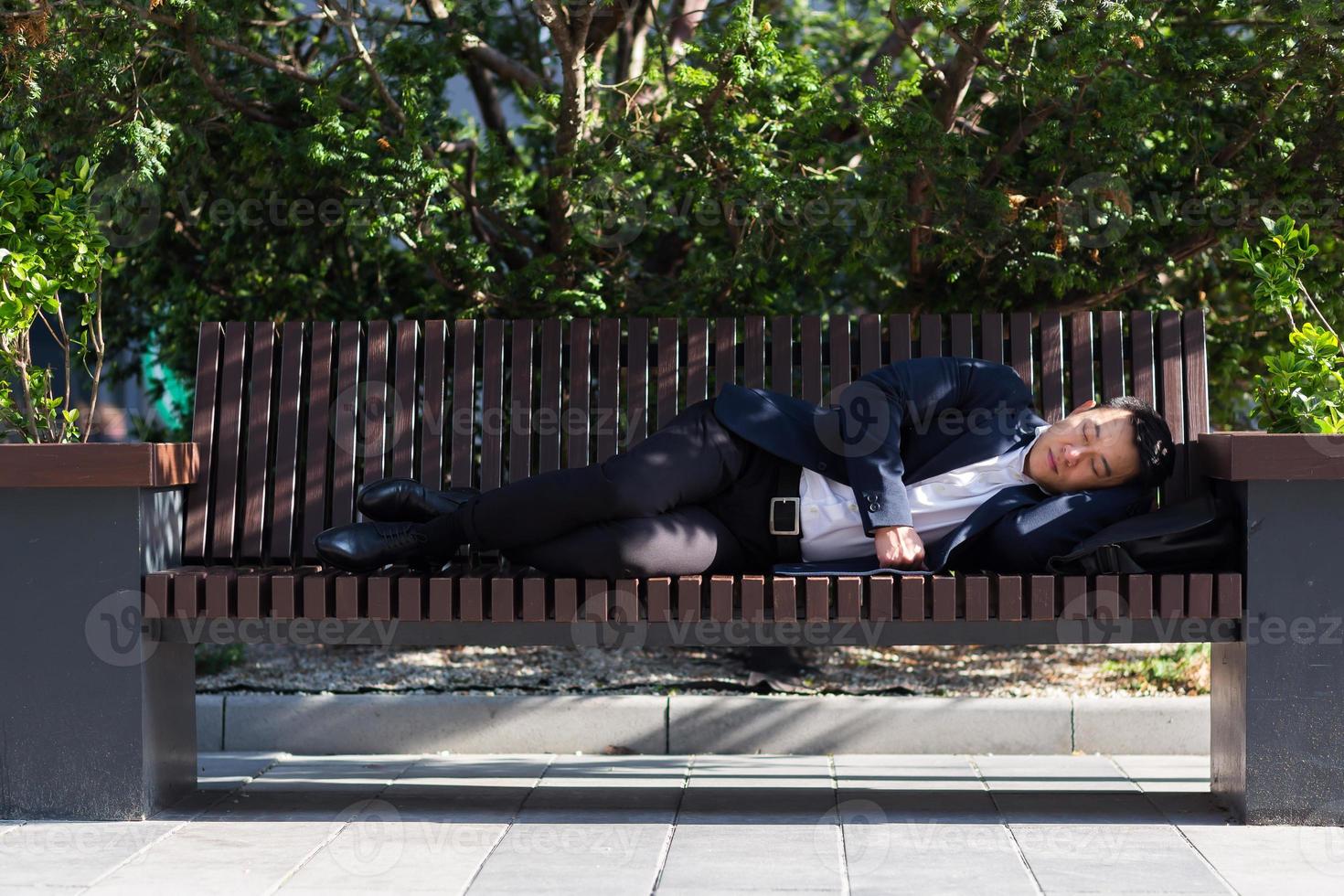 A tired Asian worker is lying in front of the company during a break from work. photo