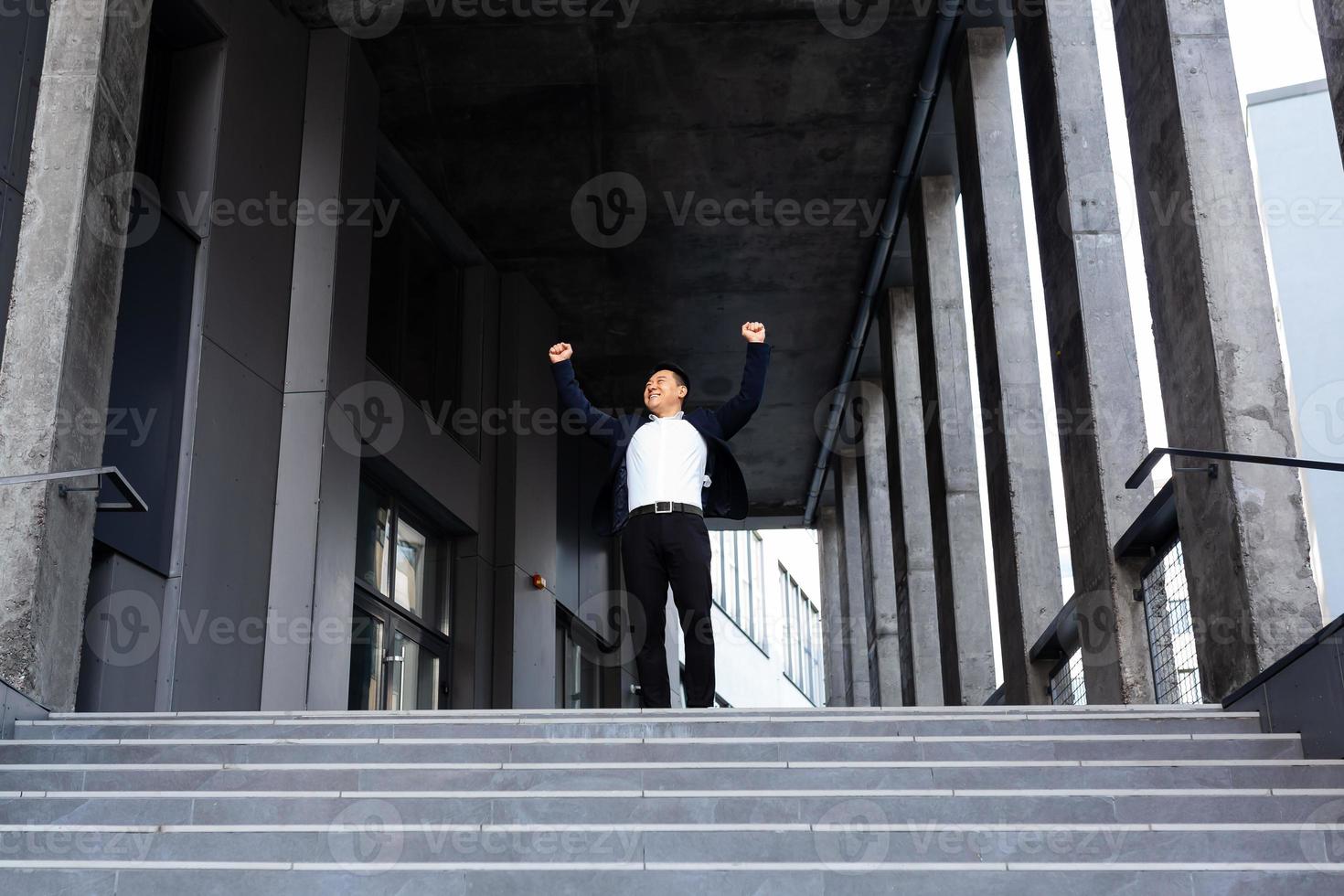 Happy and cheerful asian businessman holding hands up rejoicing in victory and success photo