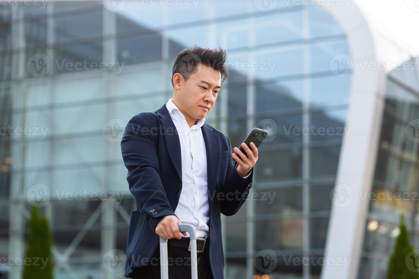 Businessman trying to call a taxi using an app and a mobile phone, asian man at the train photo