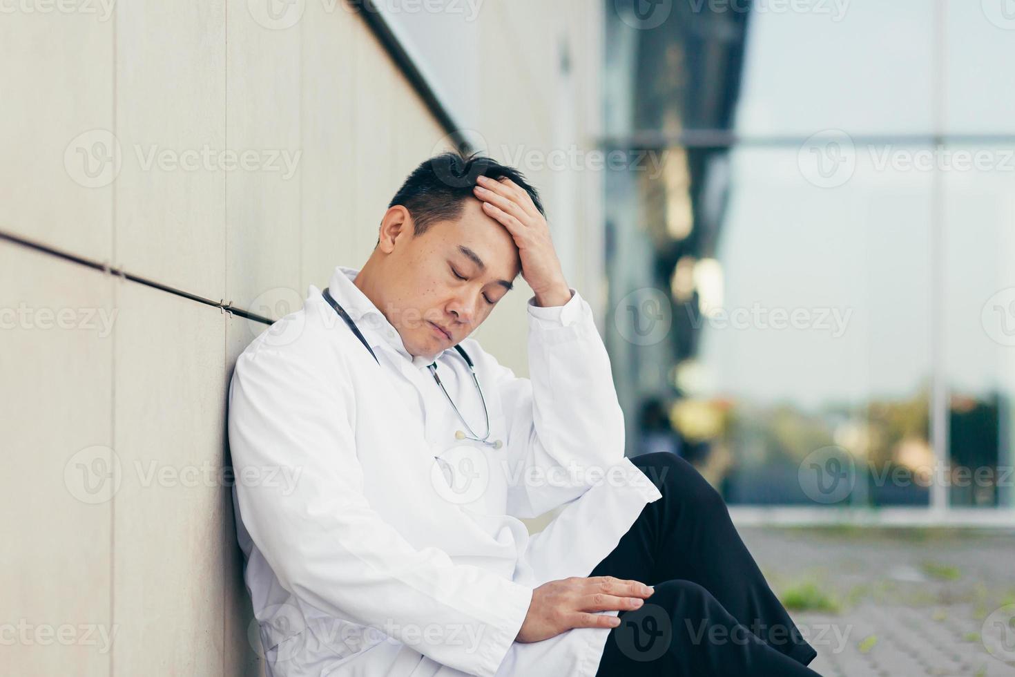 portrait Doctor Asian man tired after work sitting on the floor near the clinic disappointed photo