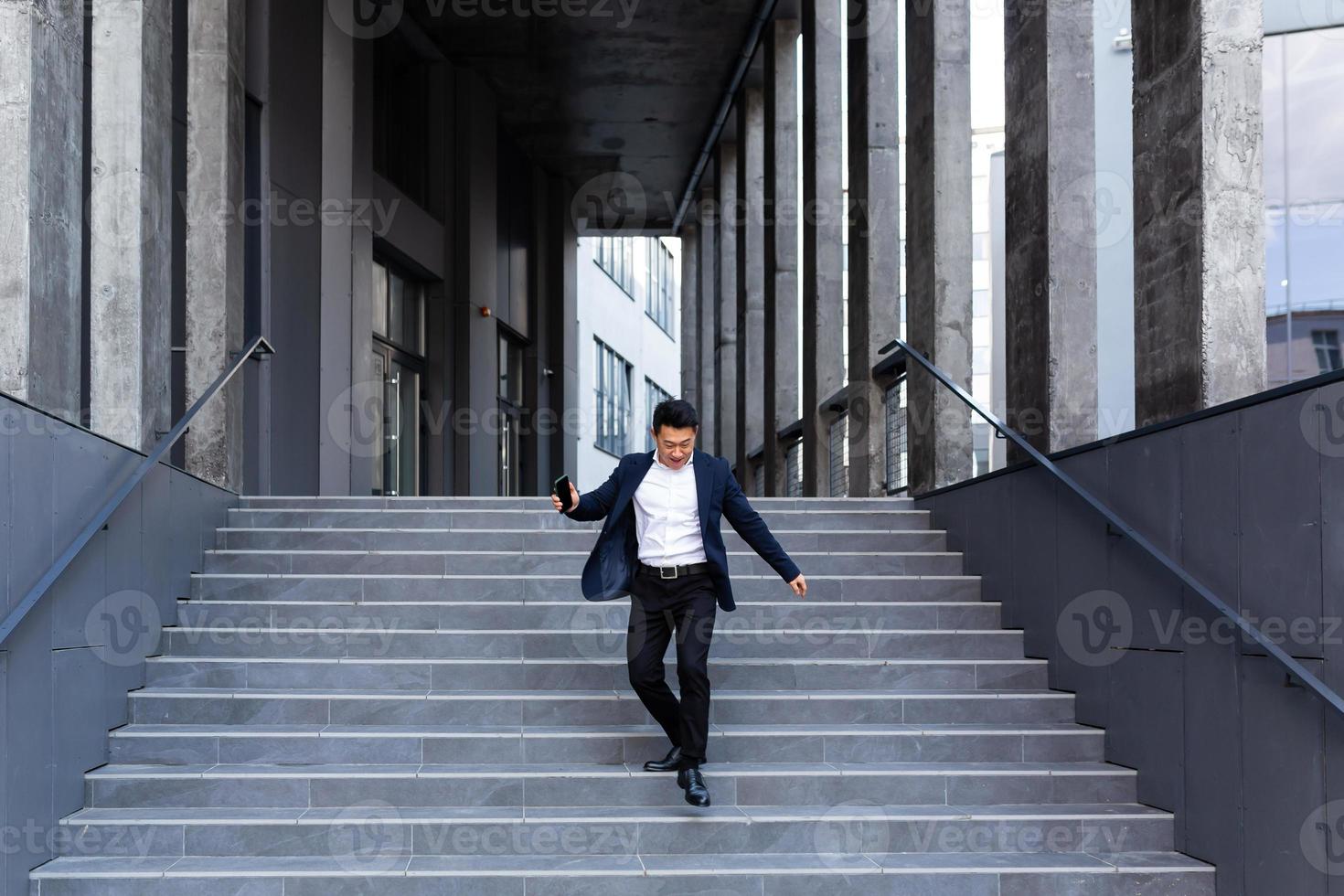 Happy and cheerful Asian businessman dancing near the office rejoices in victory and success photo