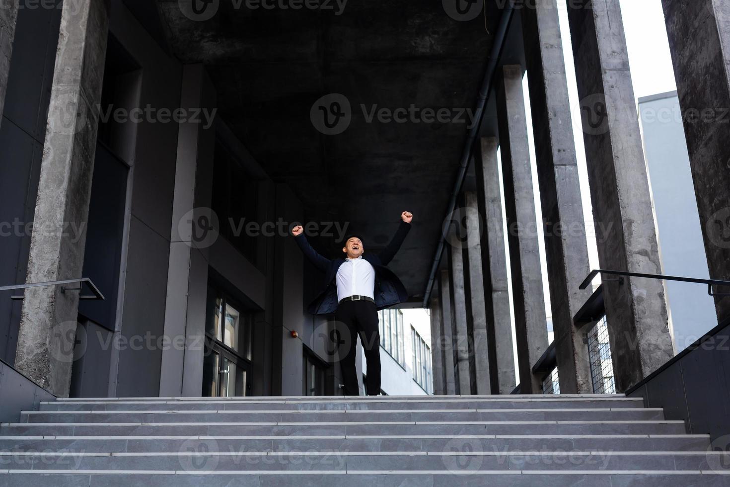 Happy and cheerful asian businessman holding hands up rejoicing in victory and success photo