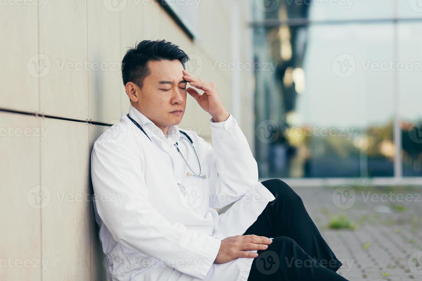 portrait Doctor Asian man tired after work sitting on the floor near the clinic disappointed photo