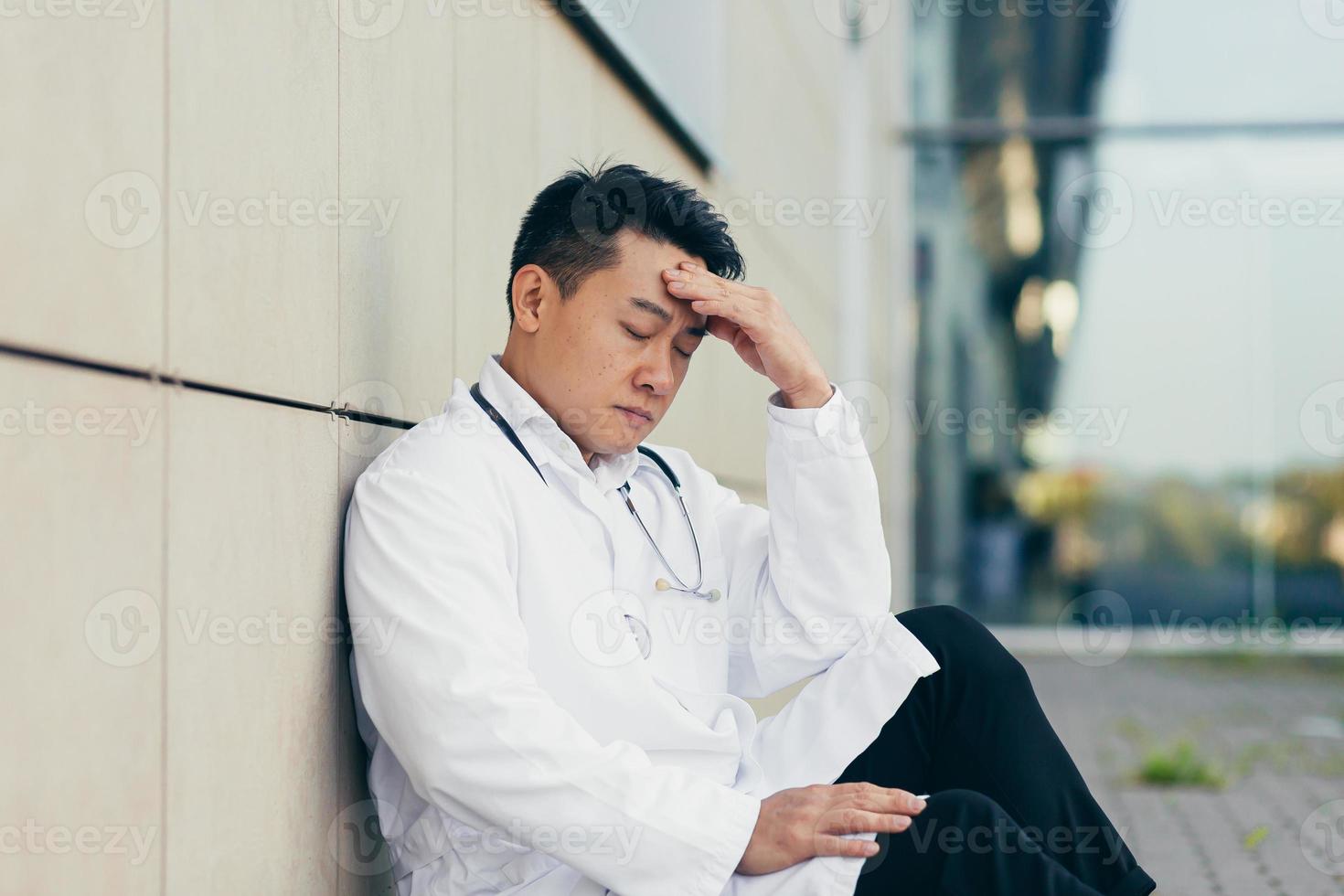 portrait Doctor Asian man tired after work sitting on the floor near the clinic disappointed photo