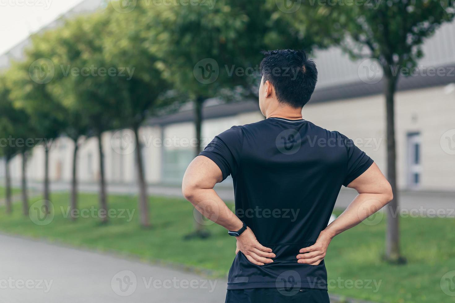 Asian man holding back pain after running and fitness photo