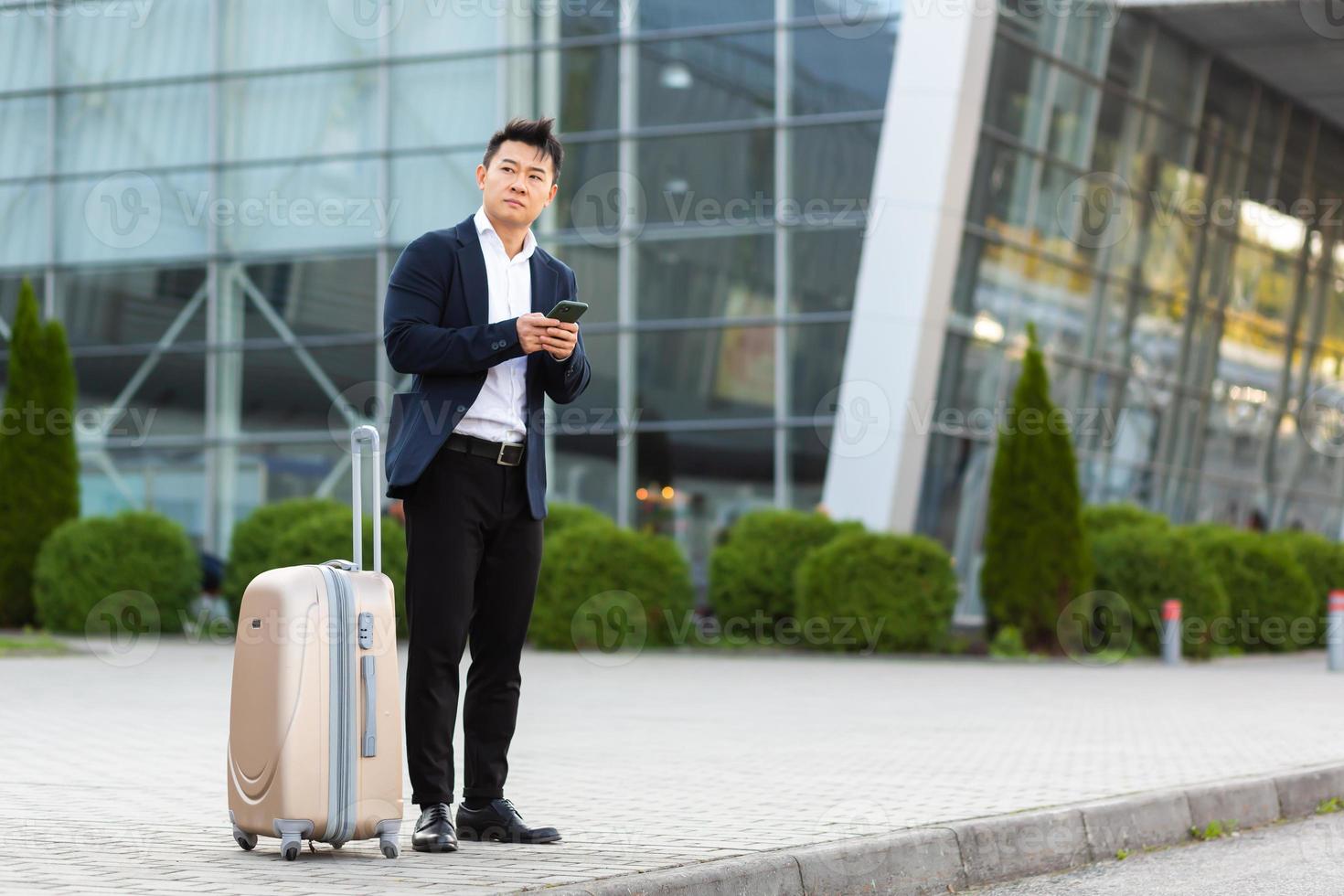Businessman trying to call a taxi using an app and a mobile phone, asian man photo