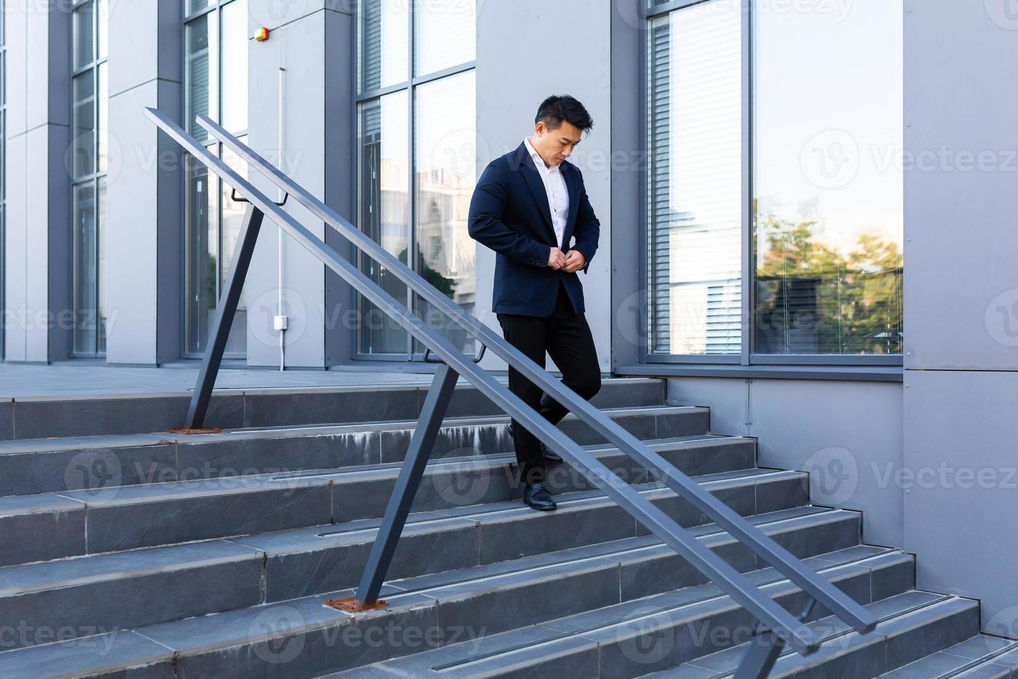 Asian businessman walks up the stairs of the office center, man hurries to a business photo