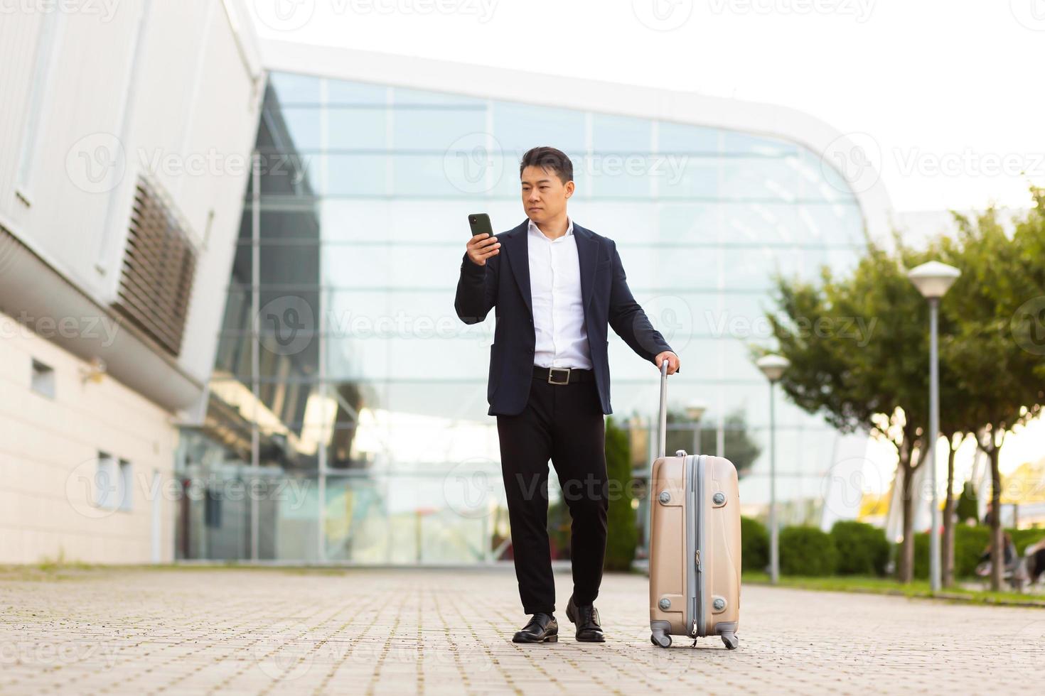 Businessman trying to call a taxi using an app and a mobile phone, asian man photo
