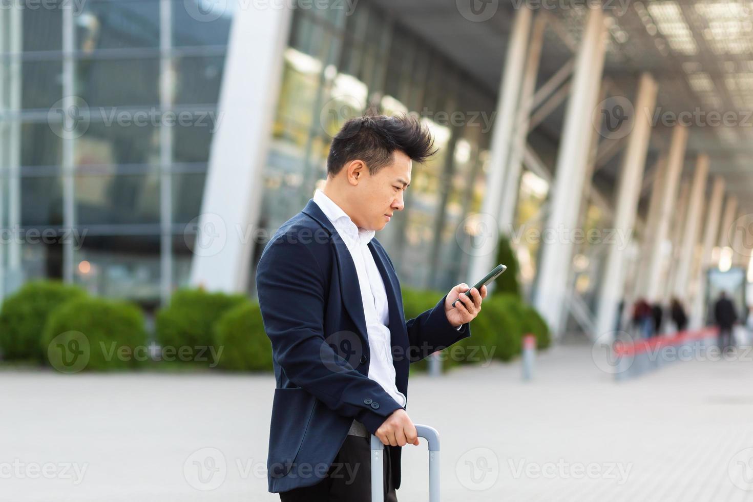 Businessman trying to call a taxi using an app and a mobile phone, asian man at the train photo