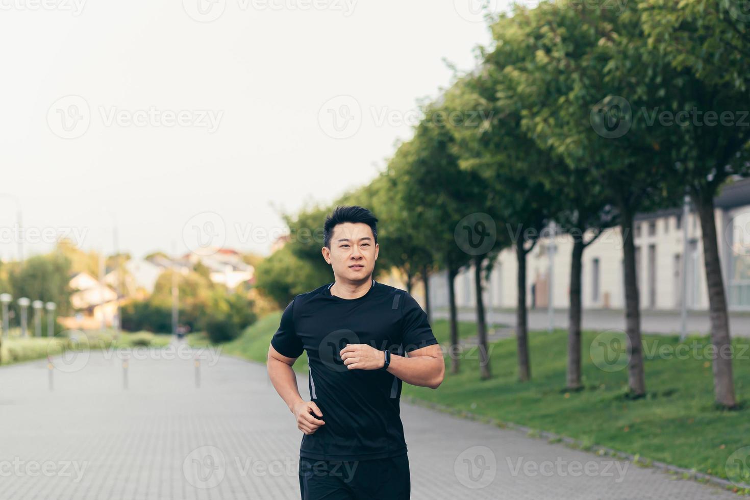 Male asian athlete on a morning run in the park near the stadium photo