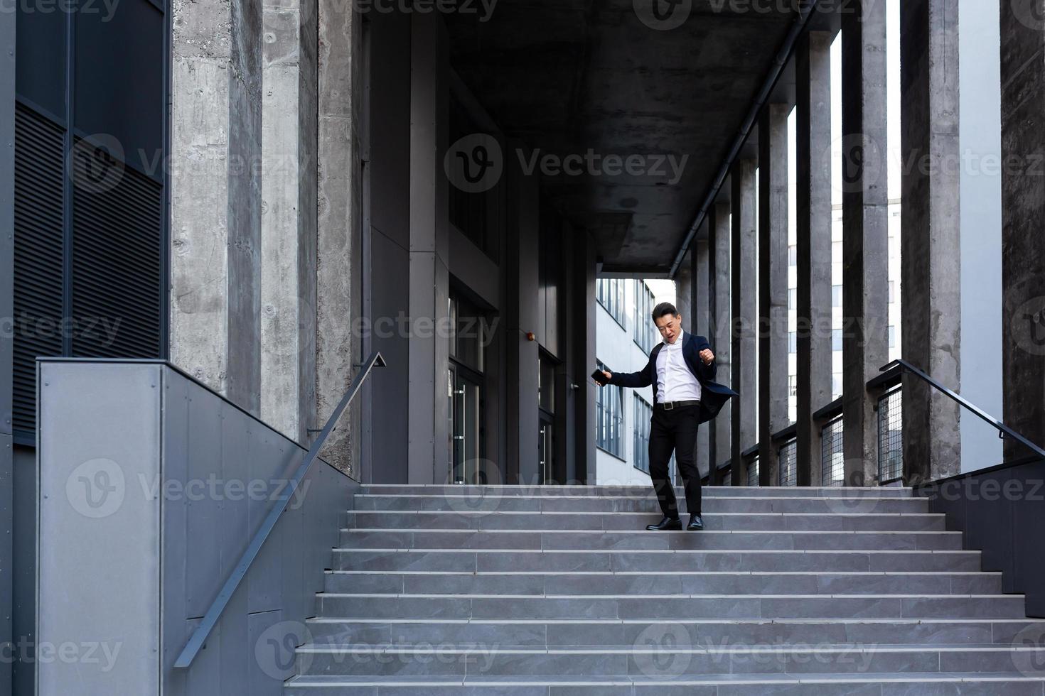 Happy and cheerful Asian businessman dancing near the office rejoices in victory and success photo