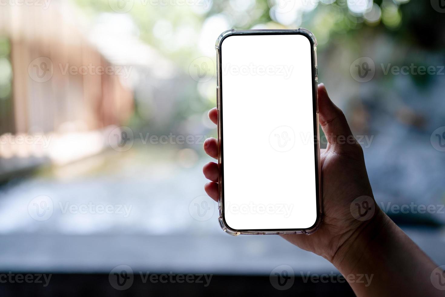 Hands holding white mobile phone with blank screen mock up, hotel spa background. photo