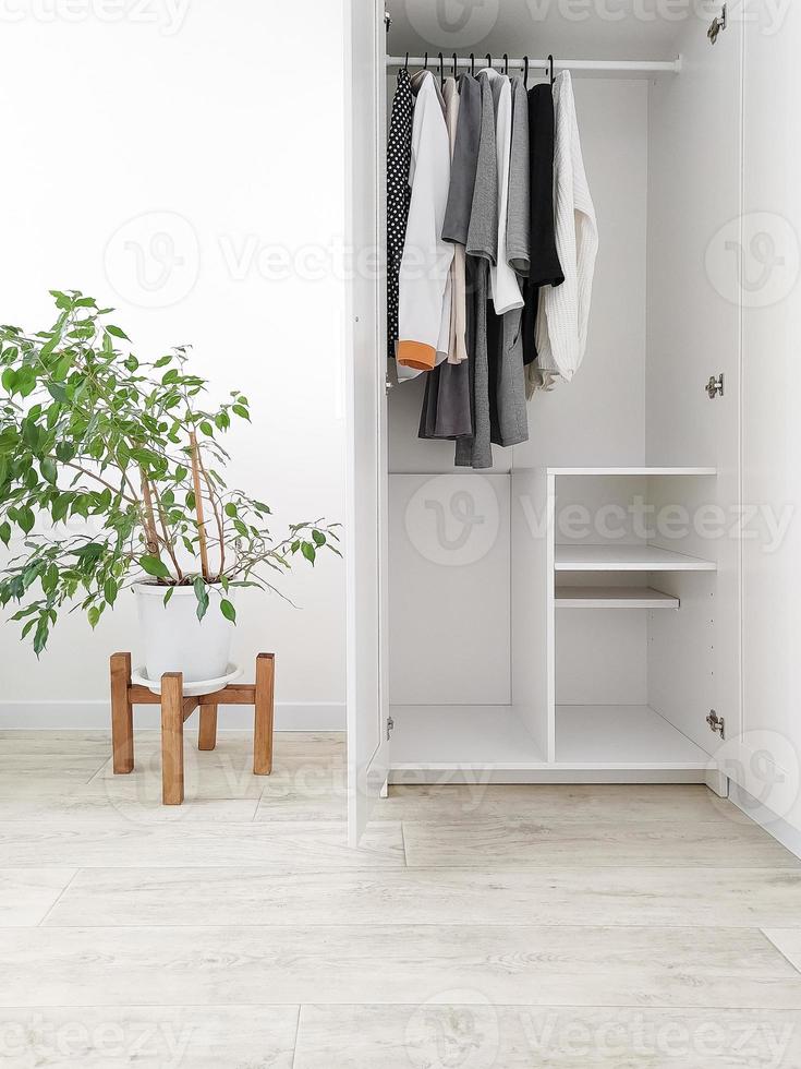 Wardrobe with basic clothes in room scandi interior. photo