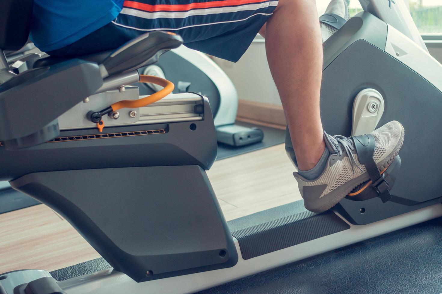 joven usando una bicicleta estática en un gimnasio interior foto