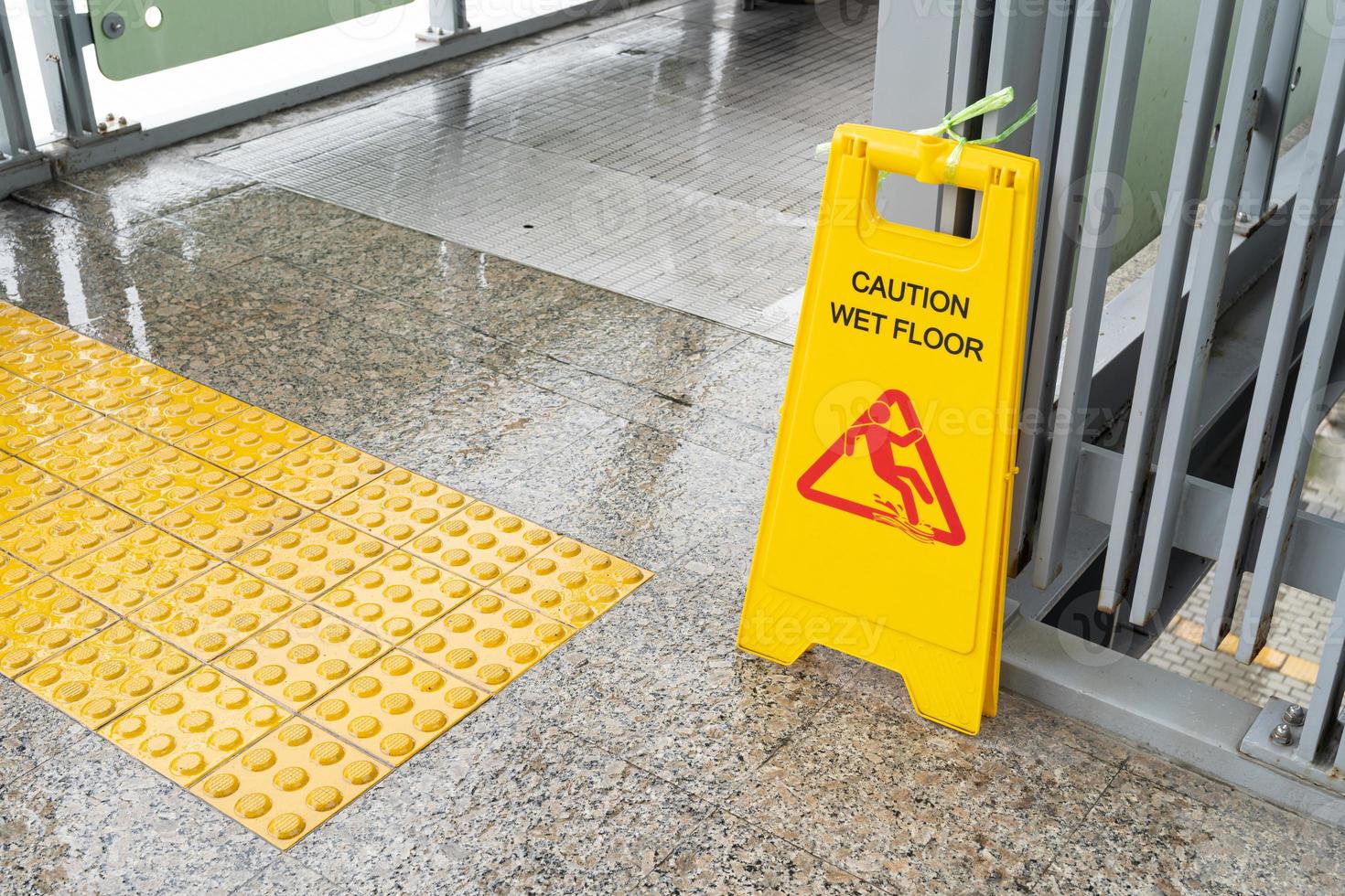 Yellow Caution slippery wet floor sign on the wet ground photo