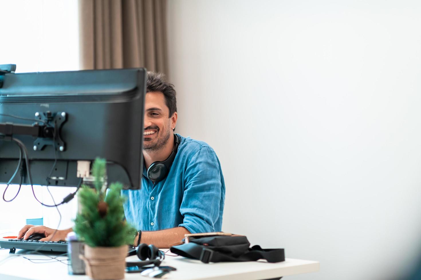 Casual man working on desktop computer in modern open plan startup office interior. Selective focus photo
