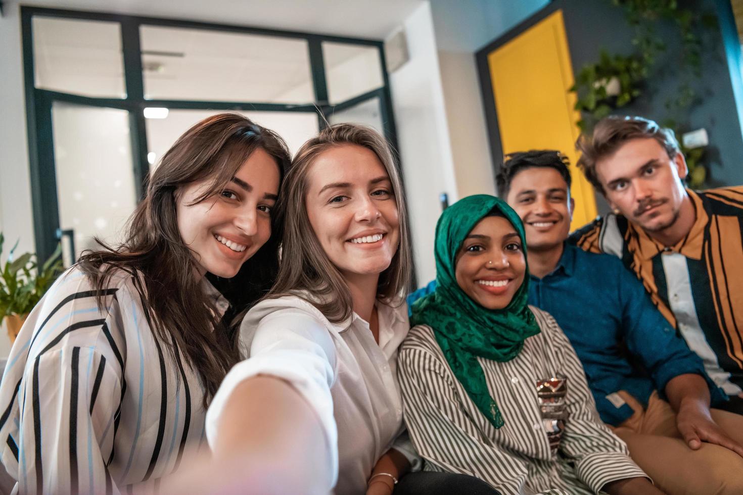 Group of business people during break from the work taking selfie picture while enjoying free time in relaxation area at modern open plan startup office. Selective focus photo