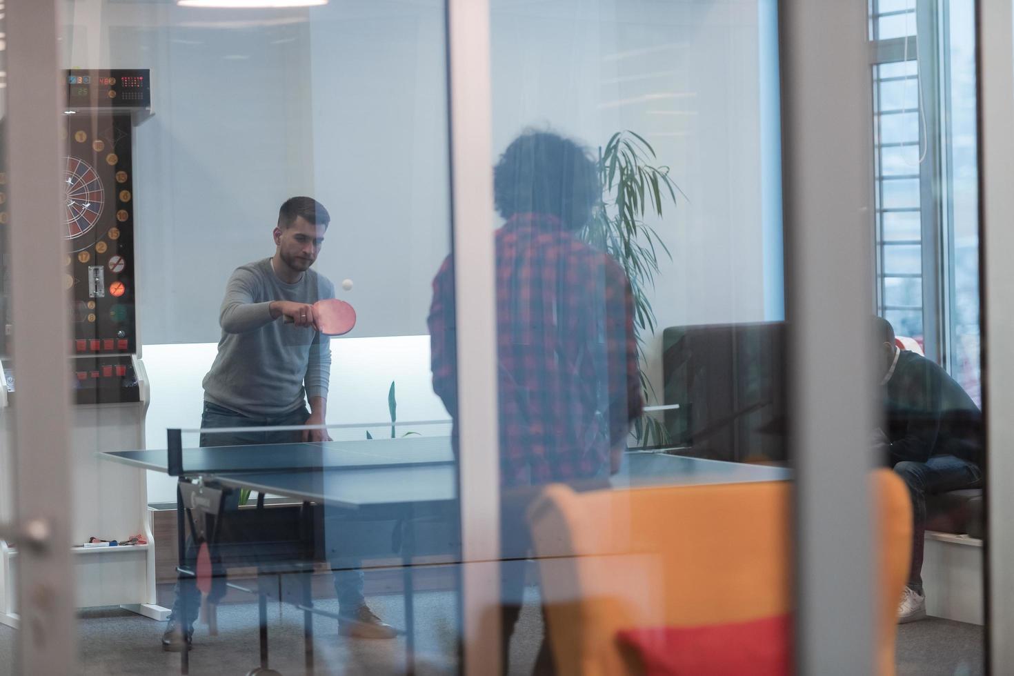 Two young start up business man playing ping pong tennis at modern creative office space people group have meeting and brainstorming in background photo