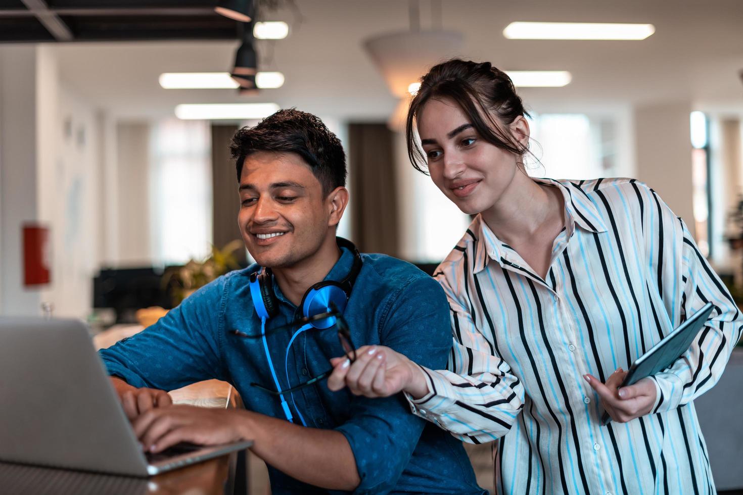 Multiethnic business people man with a female colleague working together on tablet and laptop computer in relaxation area of modern startup office photo