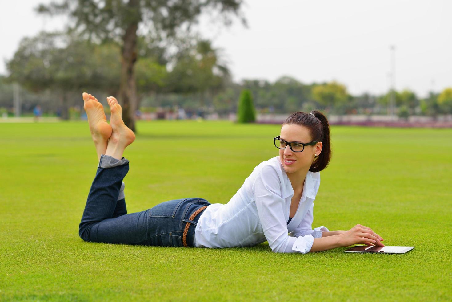 hermosa mujer joven con tableta en el parque foto