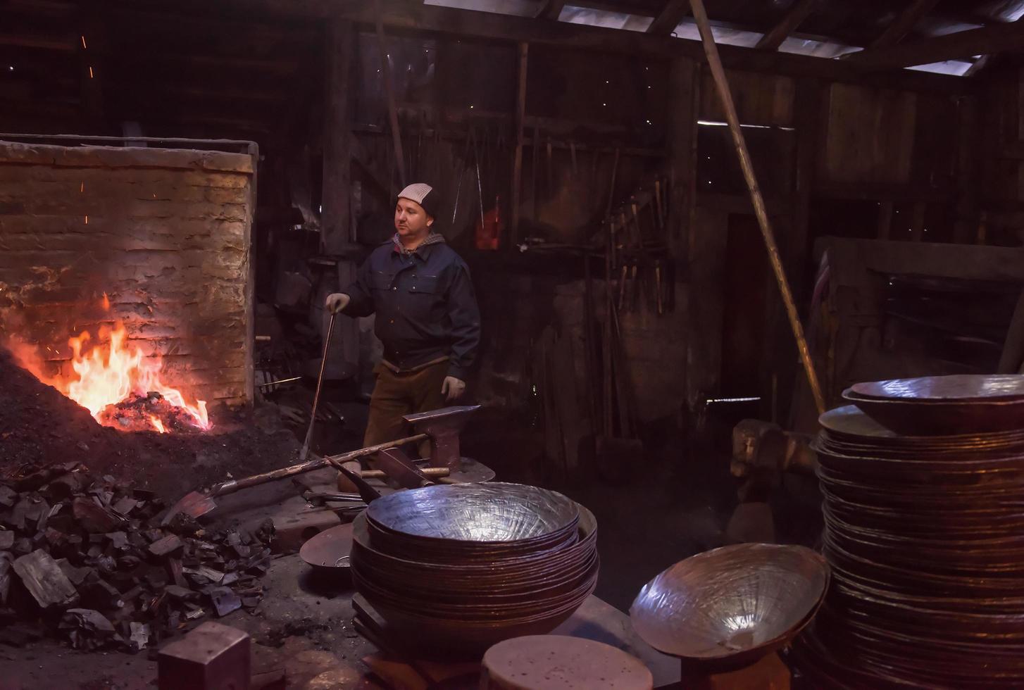 joven herrero tradicional trabajando con fuego abierto foto