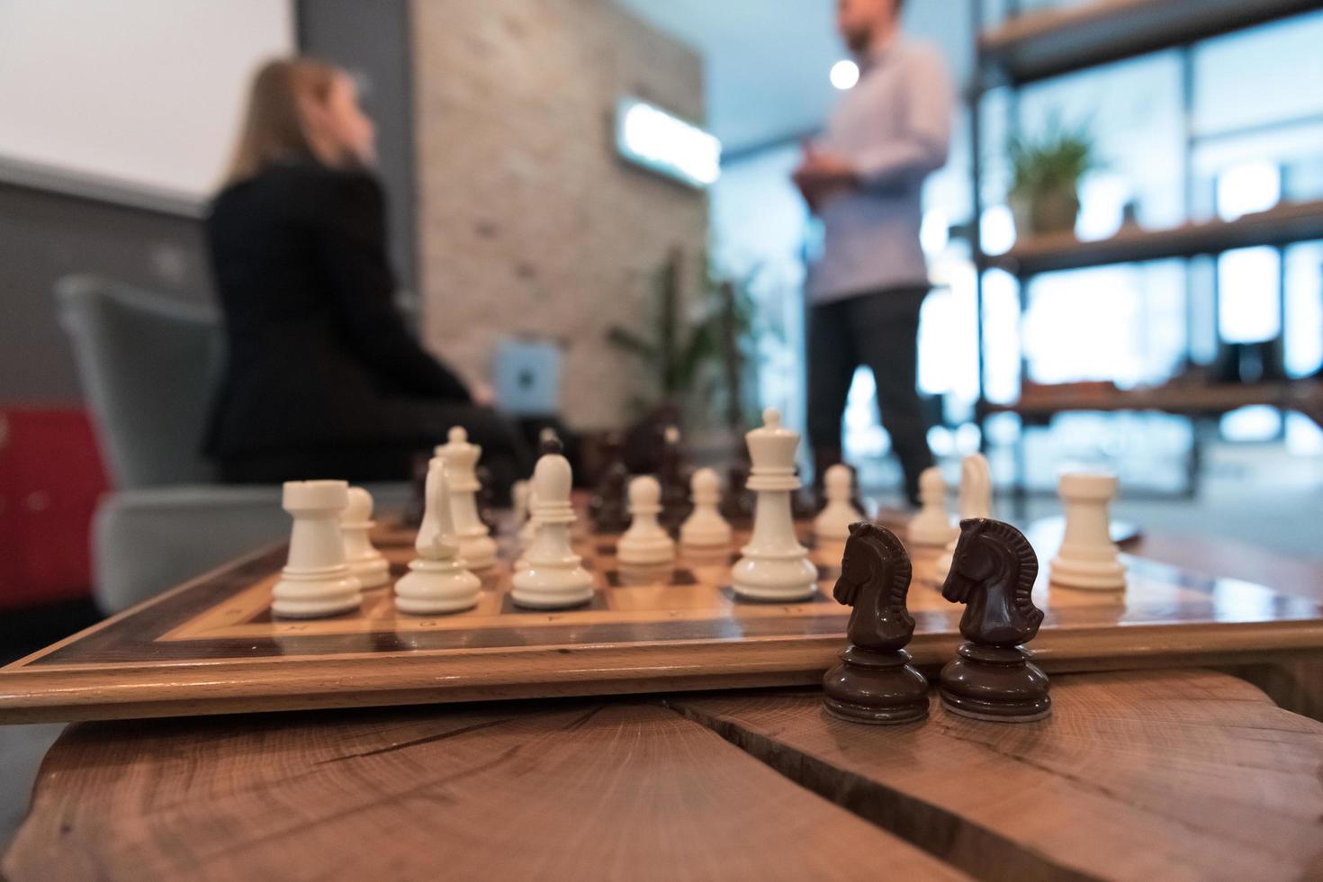 Chess pieces up close, in the background two young people on a break talking on work break photo