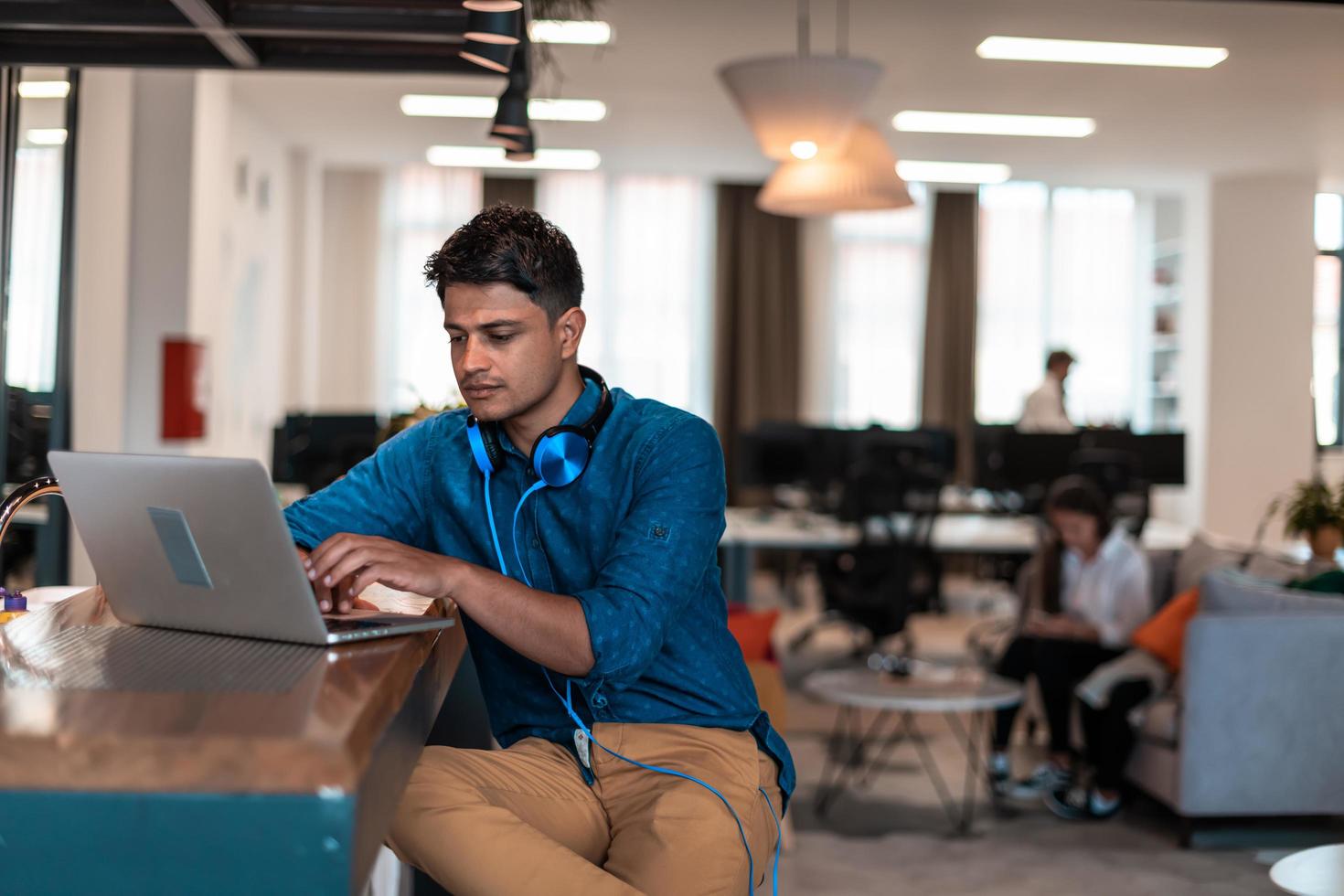 Casual business man with headphones around his using laptop for online meeting. Selective focus photo