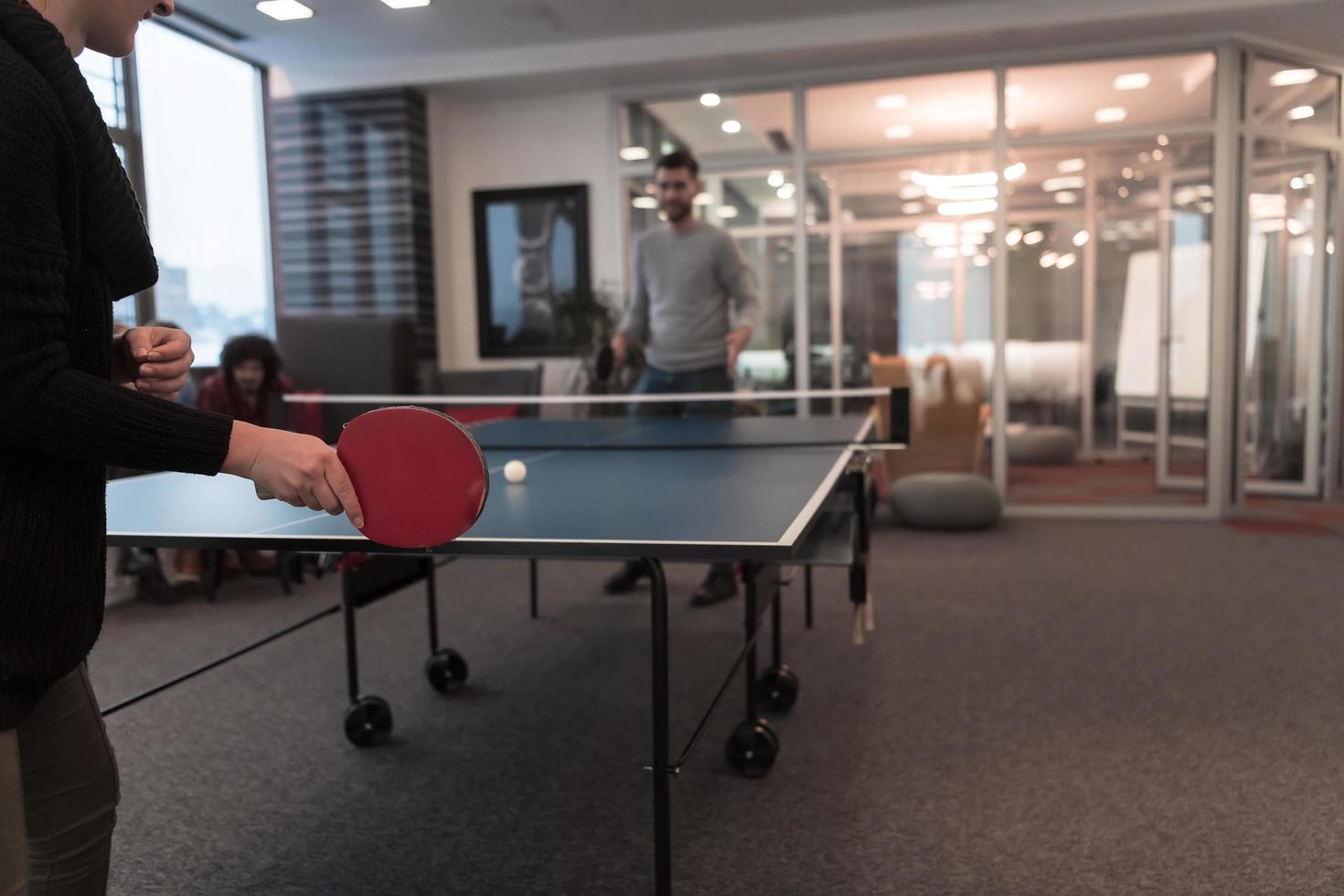 Two young start up business man playing table tennis at modern creative office space people group have meeting and brainstorming in background photo