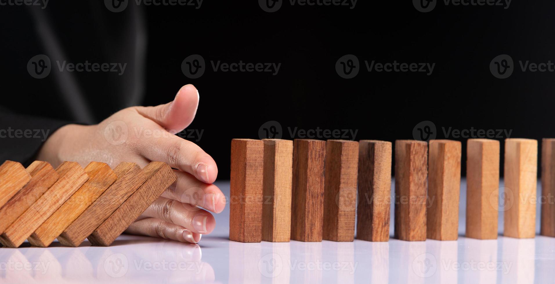 Business woman hand stop domino continuous tipping risk. Financial crisis and economic decline stop problem falling effect with success strategy management and solving opportunity concept, copy space photo