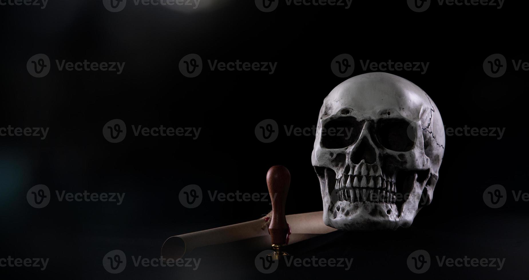 cráneo humano de halloween en una vieja mesa de madera sobre fondo negro. forma de hueso del cráneo para la cabeza de la muerte en el festival de halloween que muestra el espíritu fantasma interitance del sello de la carta de la última voluntad, espacio de copia foto