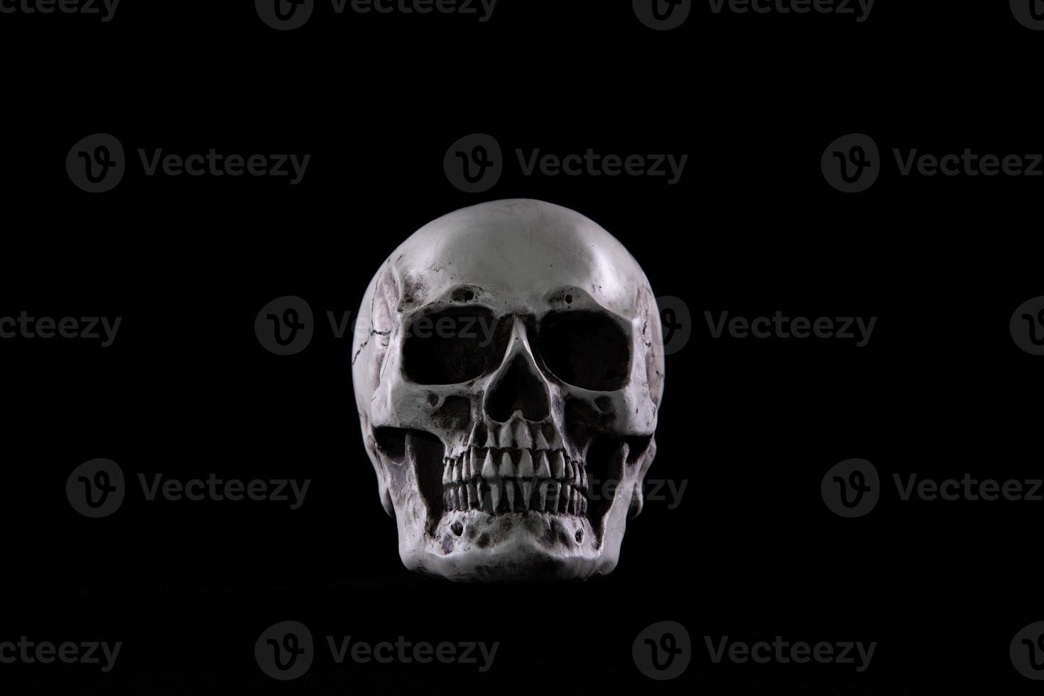 Halloween human skull on an old wooden table over black background. Shape of skull bone for Death head on halloween festival which show horror evil tooth fear and scary, copy space photo