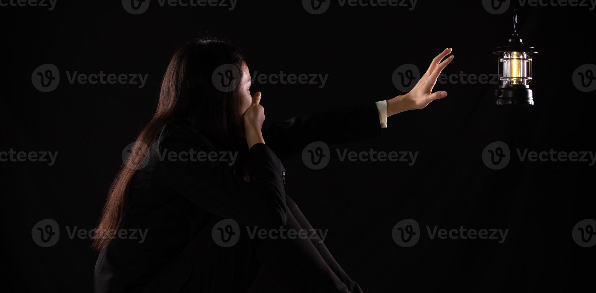 mujer de negocios triste y deprimida mirando y agarrando una lámpara de luz, sintiéndose sola cansada y preocupada sufriendo depresión en el concepto de salud mental, soledad y aislamiento. espacio de copia de bajo perfil foto