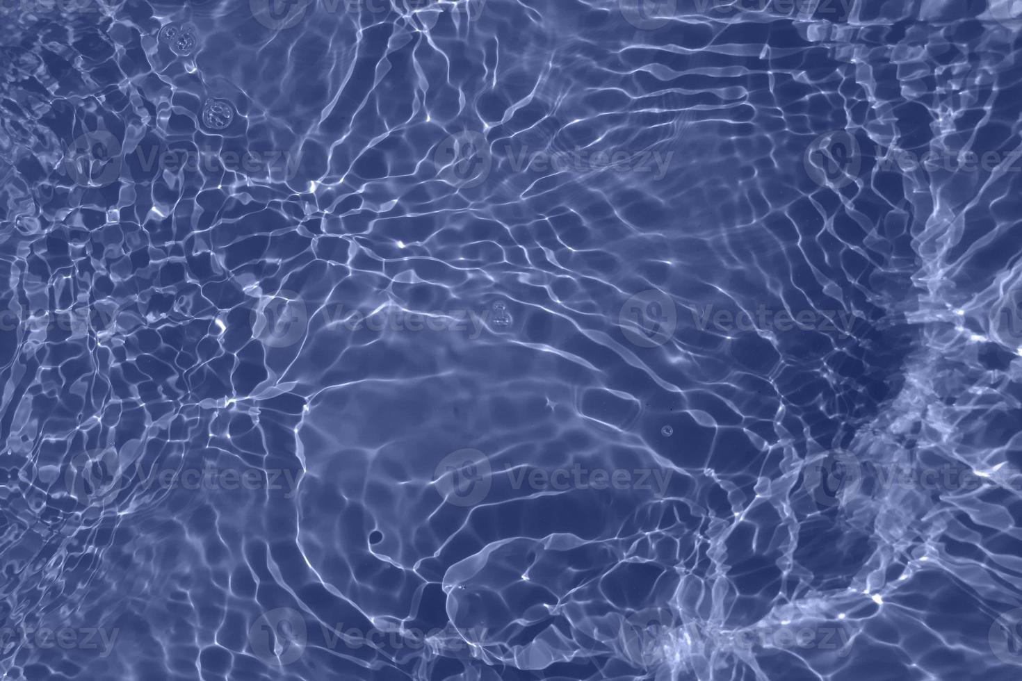 Defocus blurred transparent blue colored clear calm water surface texture with splash, bubble. Shining blue water ripple background. Surface of water in swimming pool. Blue bubble water shining. photo