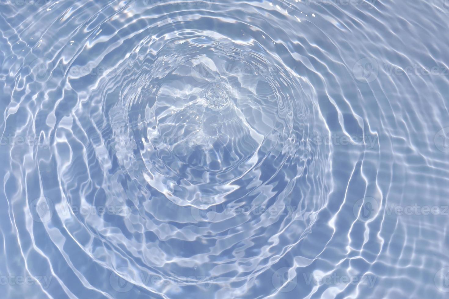 Defocus blurred transparent blue colored clear calm water surface texture with splash, bubble. Shining blue water ripple background. Surface of water in swimming pool. Blue bubble water shining. photo