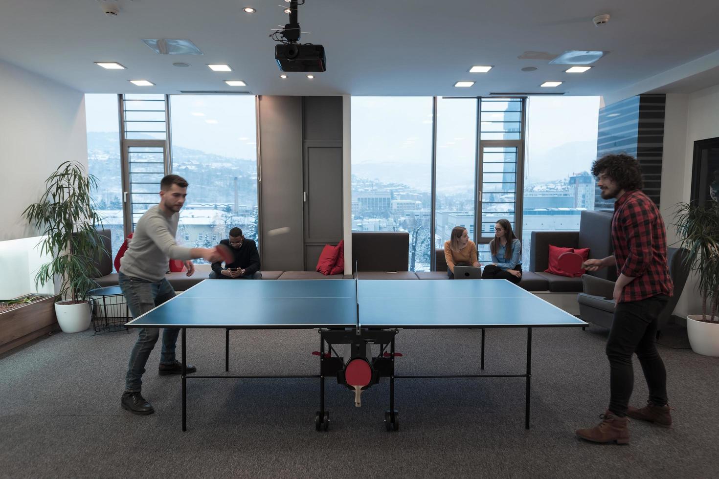 Two young start up business man playing ping pong tennis at modern creative office space people group have meeting and brainstorming in background photo