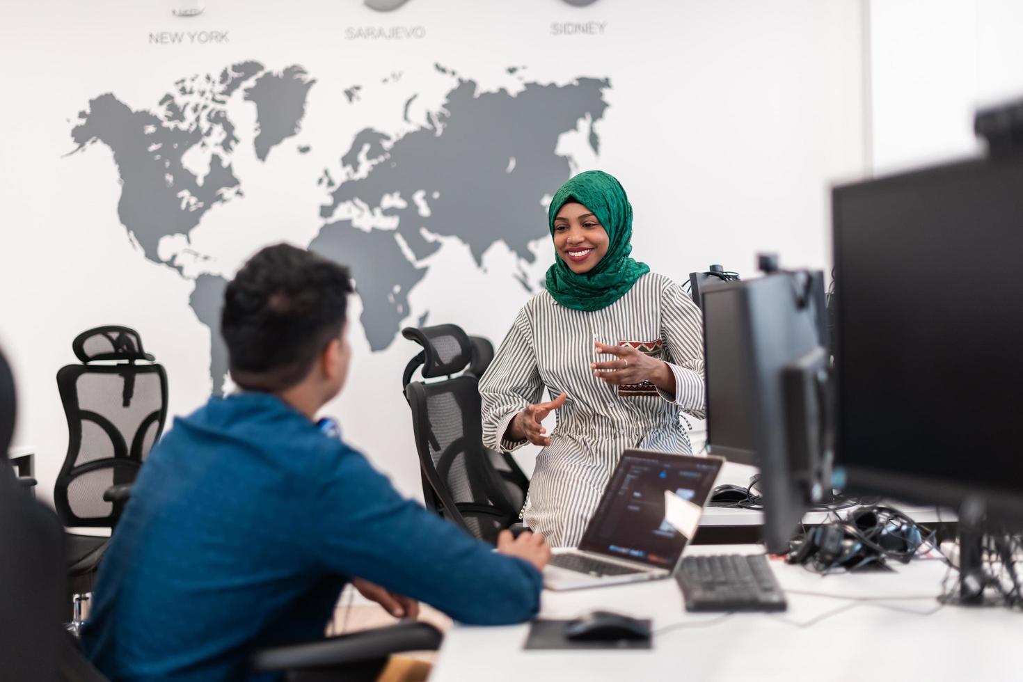 Multiethnic startup business team Arabian woman wearing a hijab on meeting in modern open plan office interior brainstorming, working on laptop and desktop computer. Selective focus photo