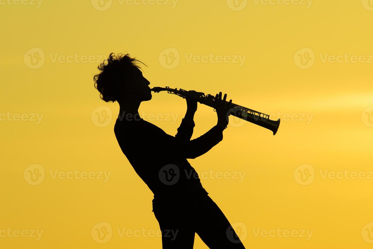 Playing saxophone silhouette on yellow background photo