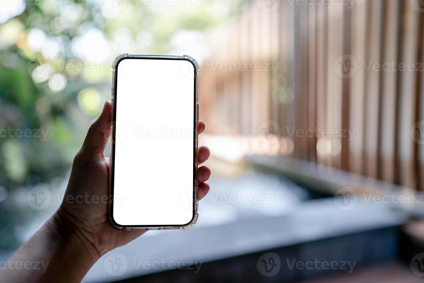 Hands holding white mobile phone with blank screen mock up, hotel spa background. photo