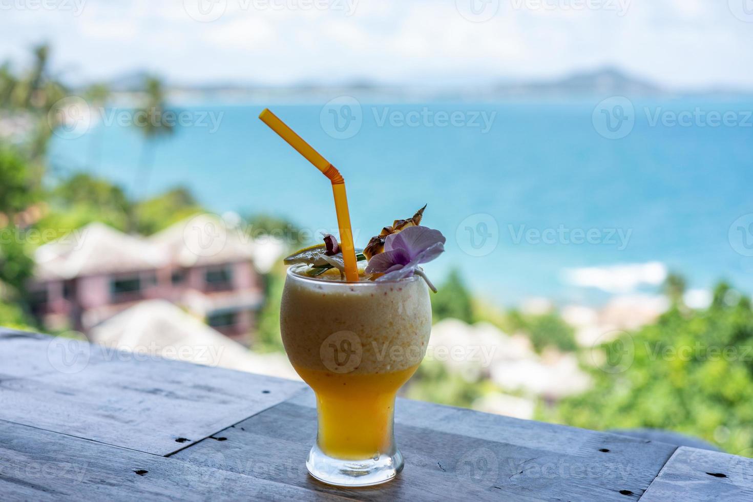 vaso de jugo de piña con fondo oceánico borroso. foto