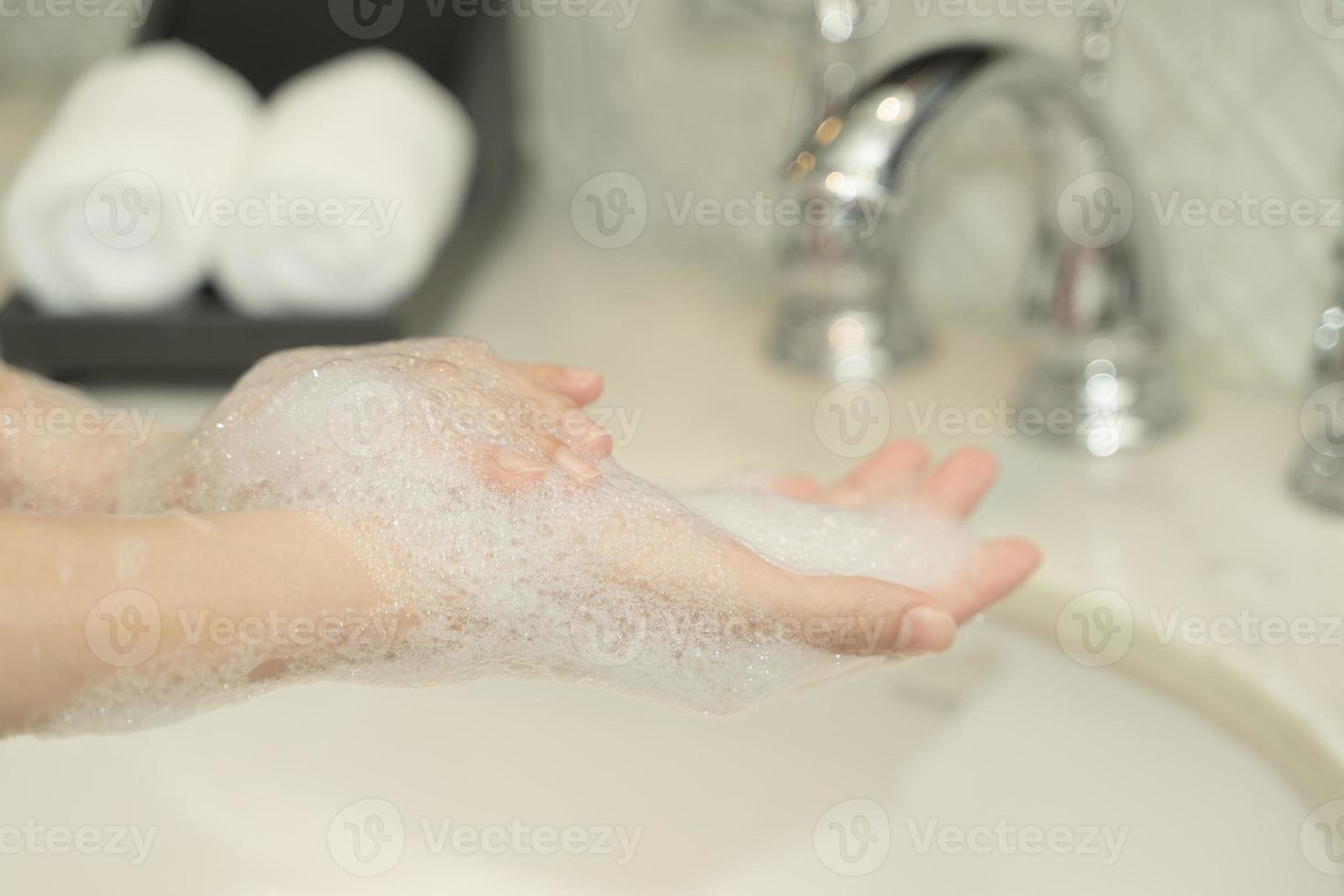 la mano de la mujer usa jabón y se lava bajo el grifo de agua. concepto de higiene. foto