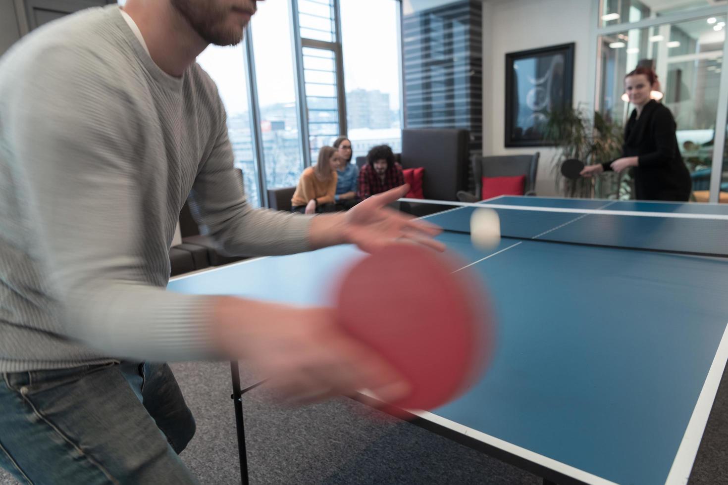 Young start up business man and woman playing table tennis at modern creative office space people group have meeting and brainstorming in background photo