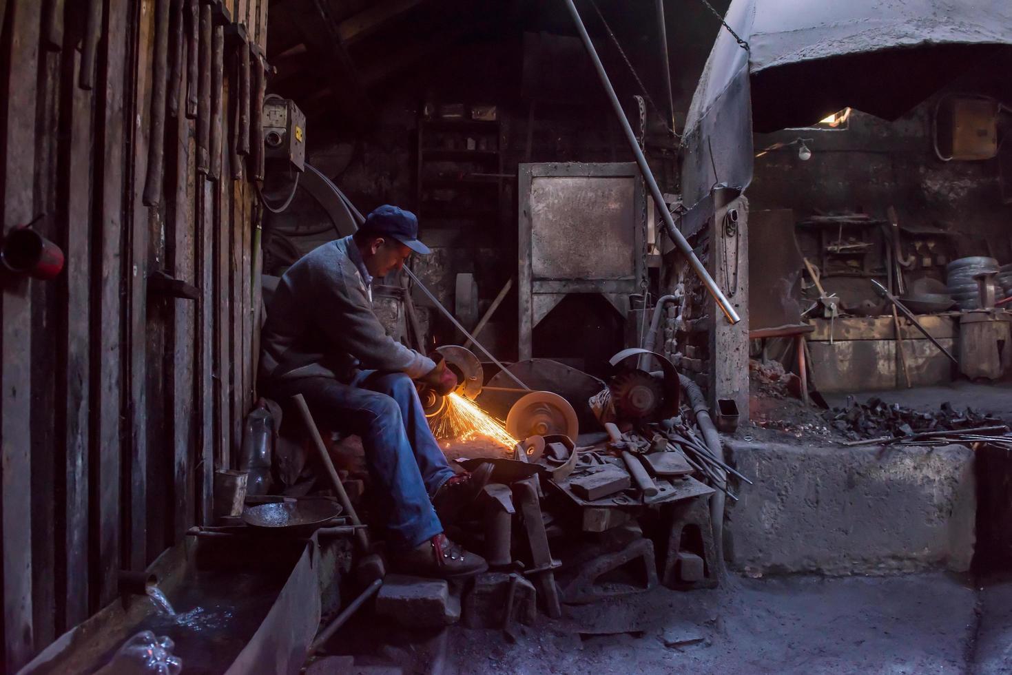 el herrero puliendo productos de metal foto