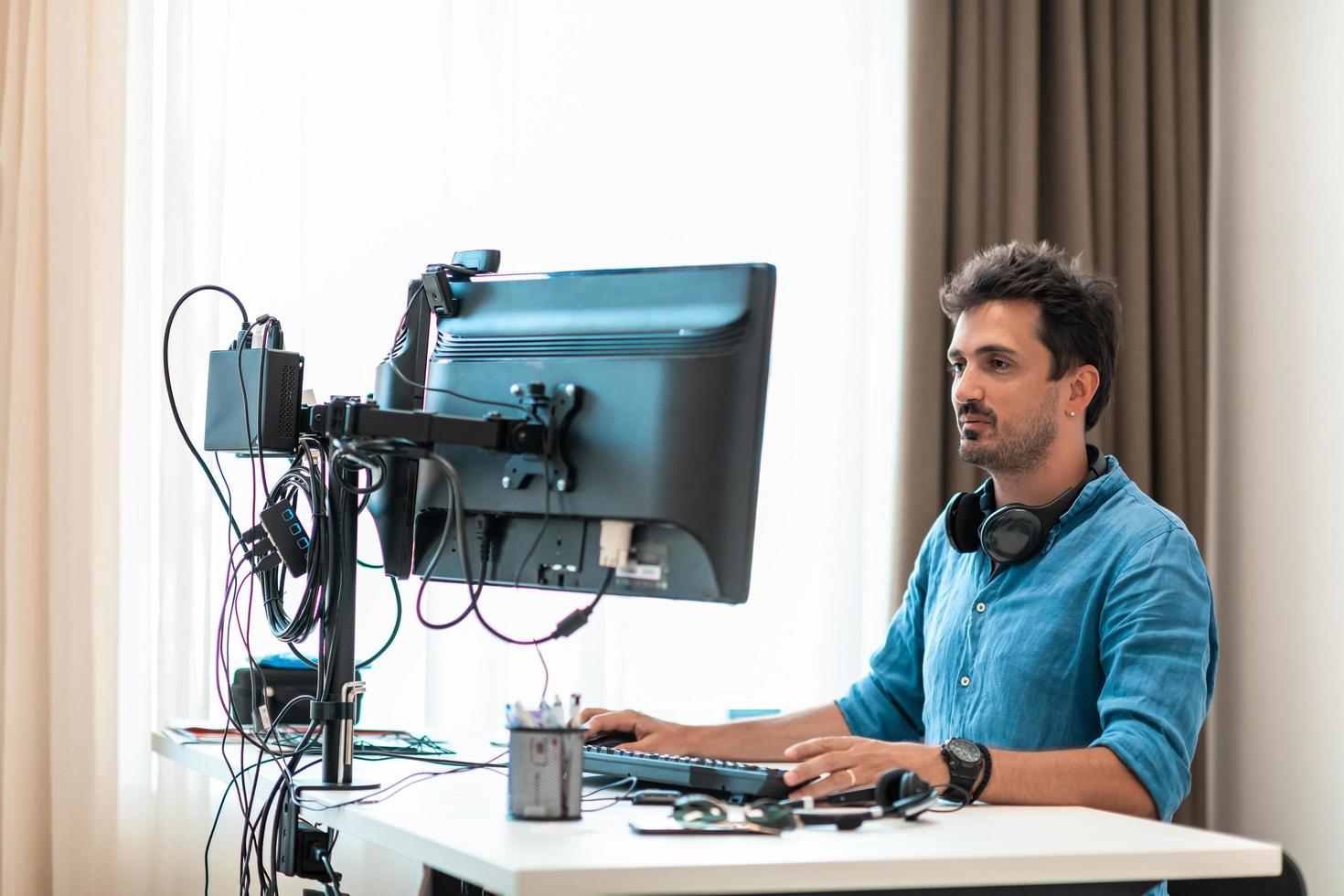 Casual man working on desktop computer in modern open plan startup office interior. Selective focus photo
