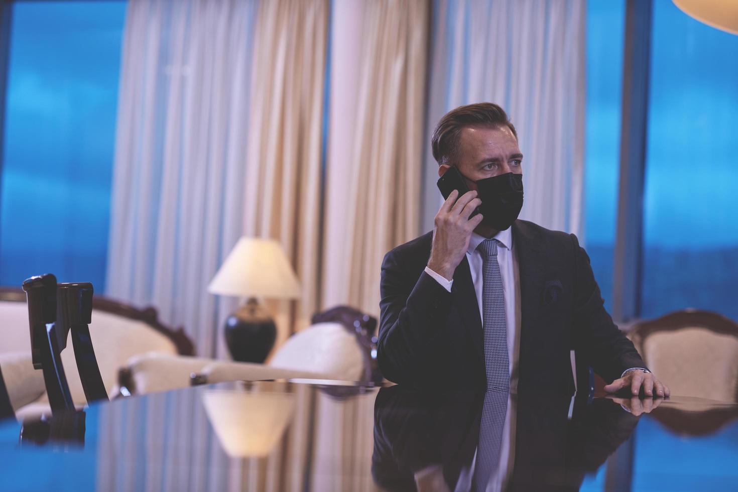 business man using smart phone at luxury office wearing face mask photo