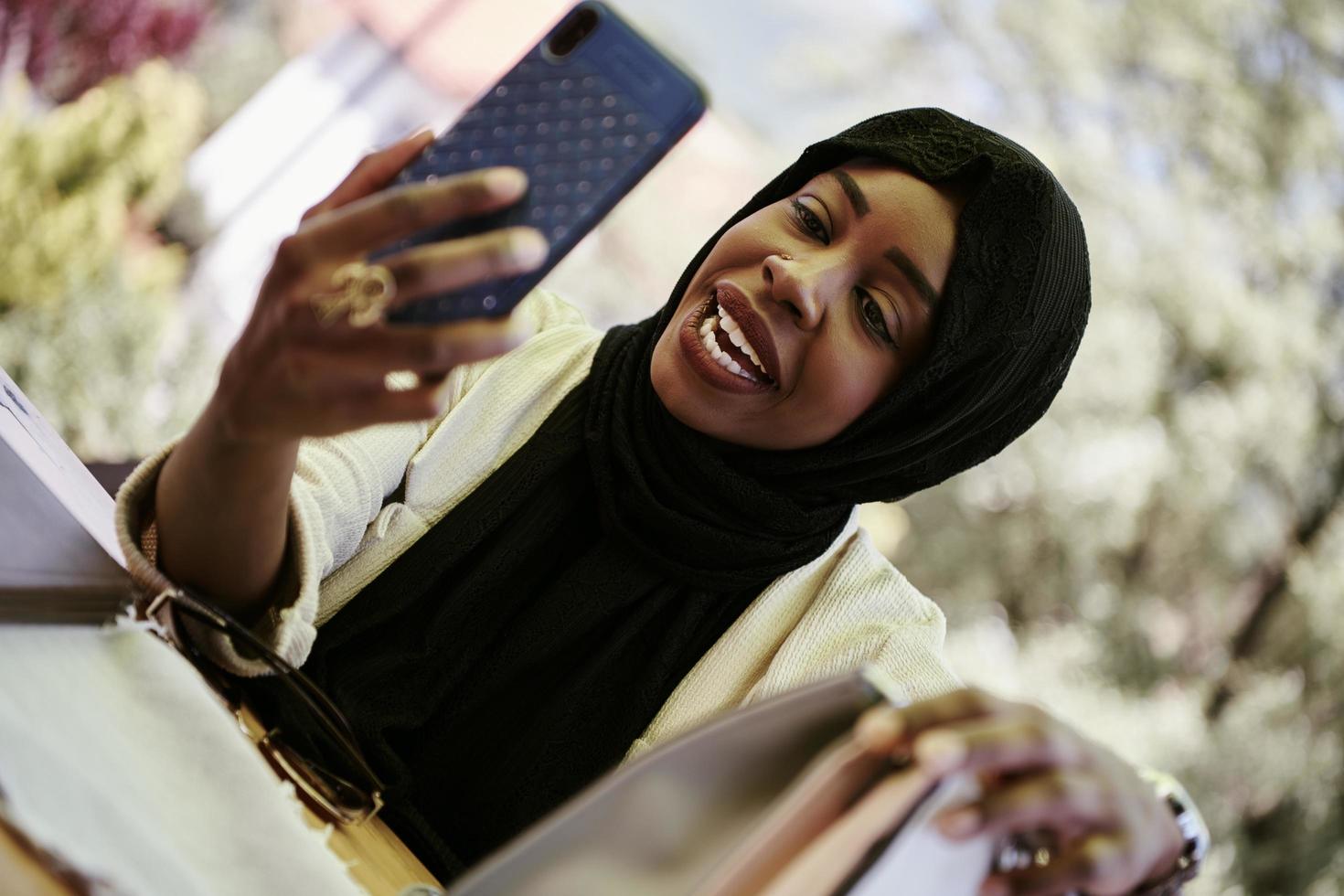 mujer africana que usa un teléfono inteligente con ropa islámica tradicional foto