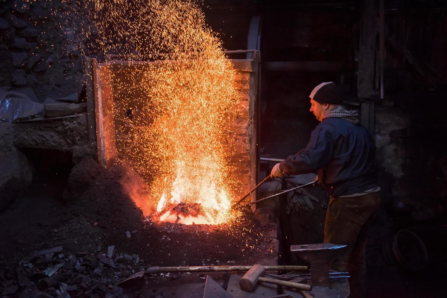 young traditional Blacksmith working with open fire photo