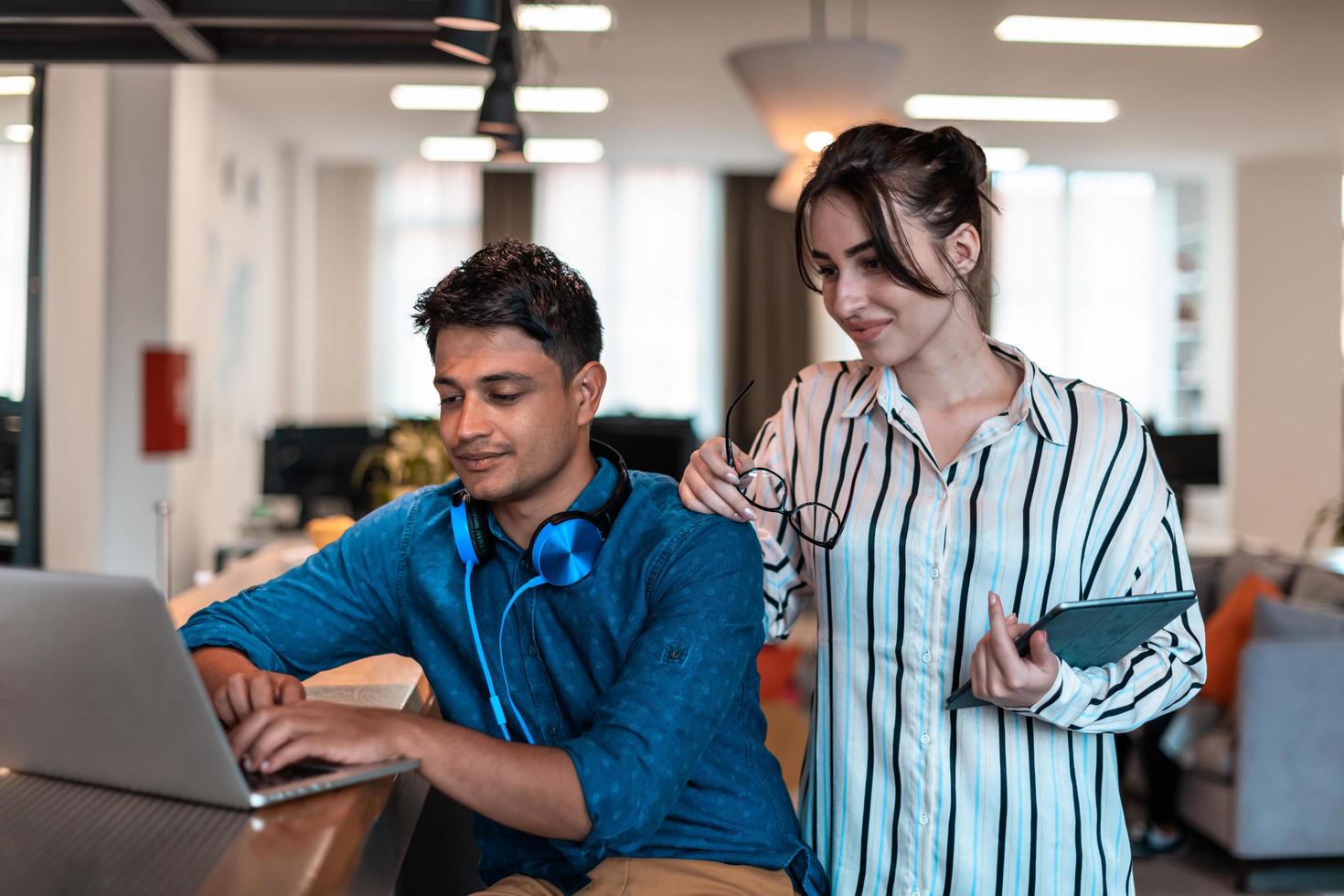 Multiethnic business people man with a female colleague working together on tablet and laptop computer in relaxation area of modern startup office photo