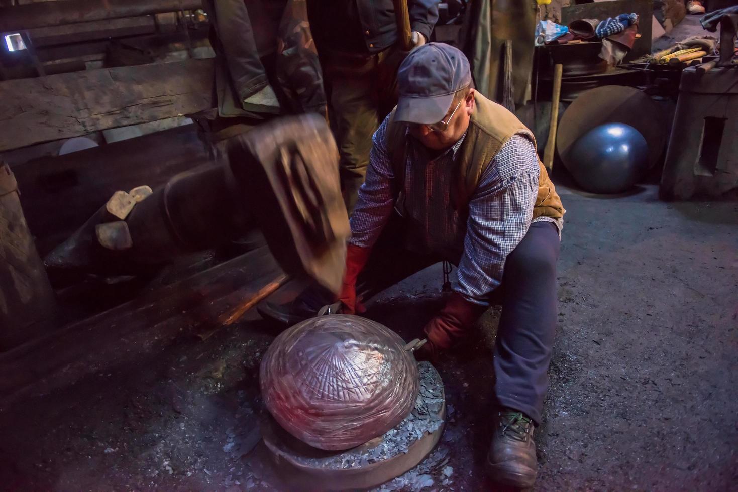 blacksmith workers using mechanical hammer at workshop photo